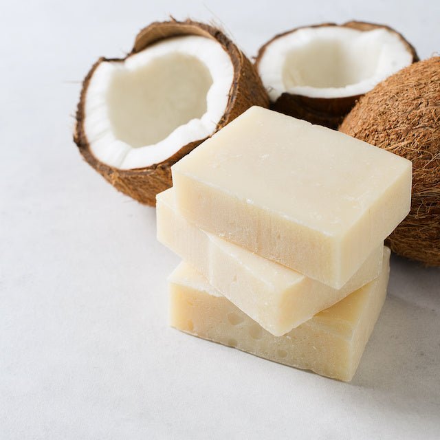 Cream soap bars stacked with fresh coconut halves behind