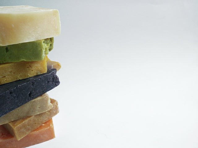 Stack of tea tree oil soap bars in assorted tones: cream, dark, green, and tan
